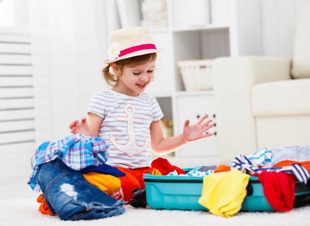 Child in front of their suitcase packing for a trip