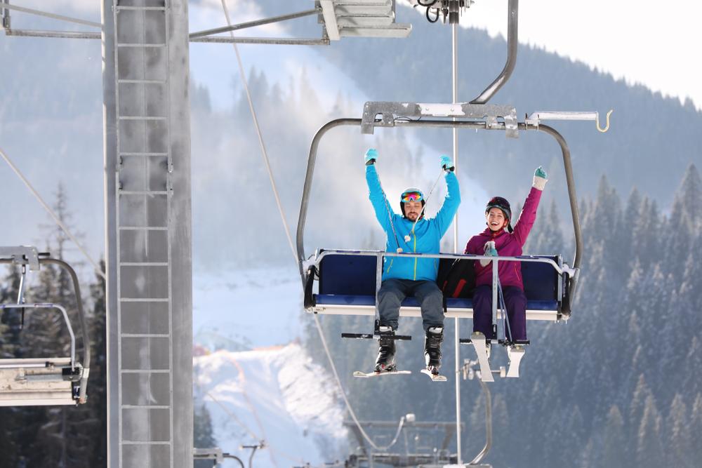 Two skiers sitting on a chairlift in the mountains