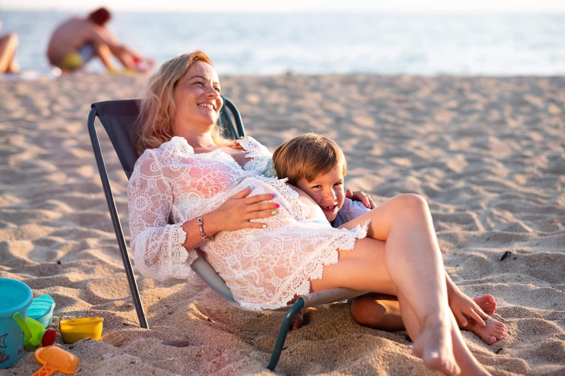 Maman enceinte à la plage avec son jeune enfant