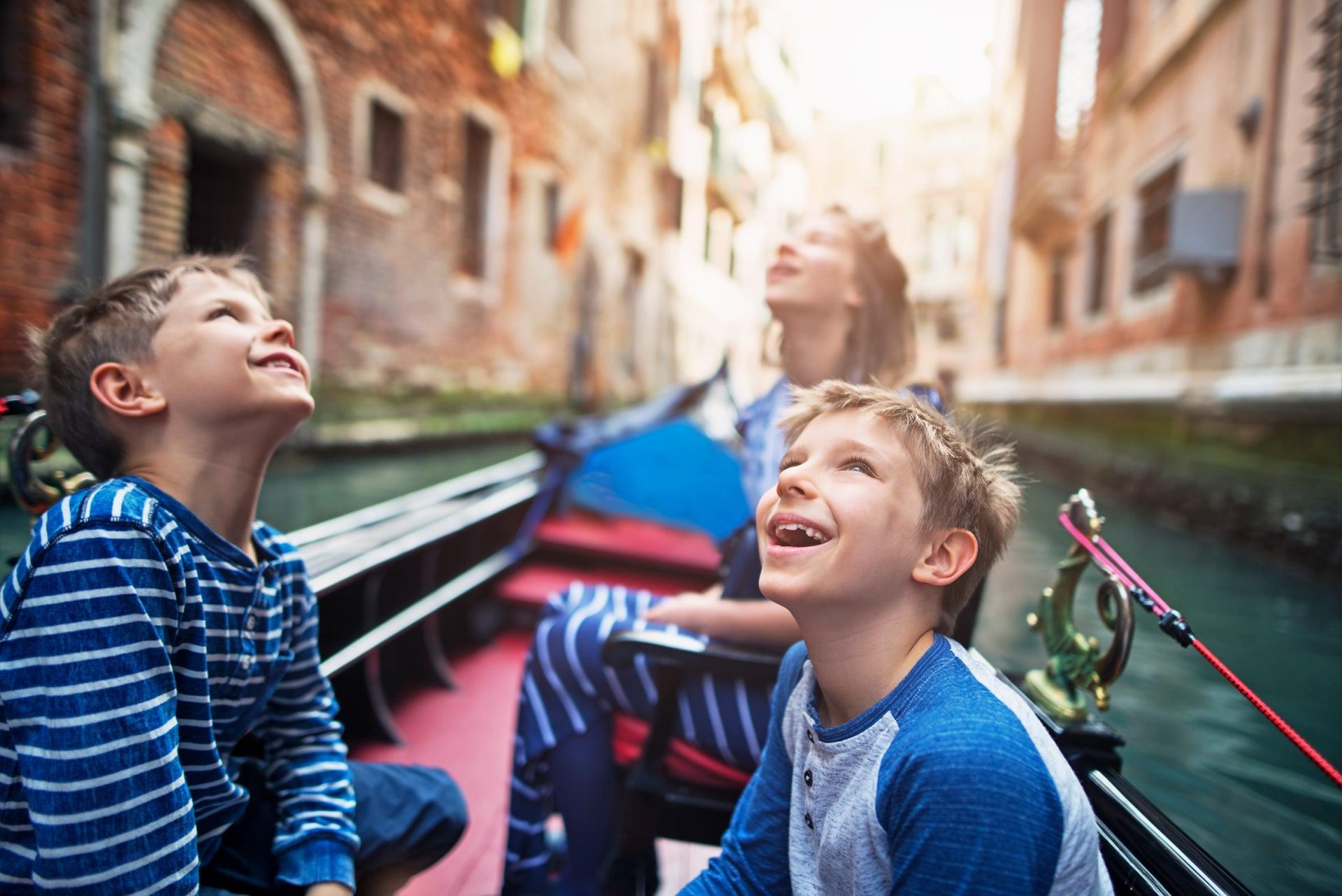 Young children visiting Venice in a gondola and admiring the buildings
