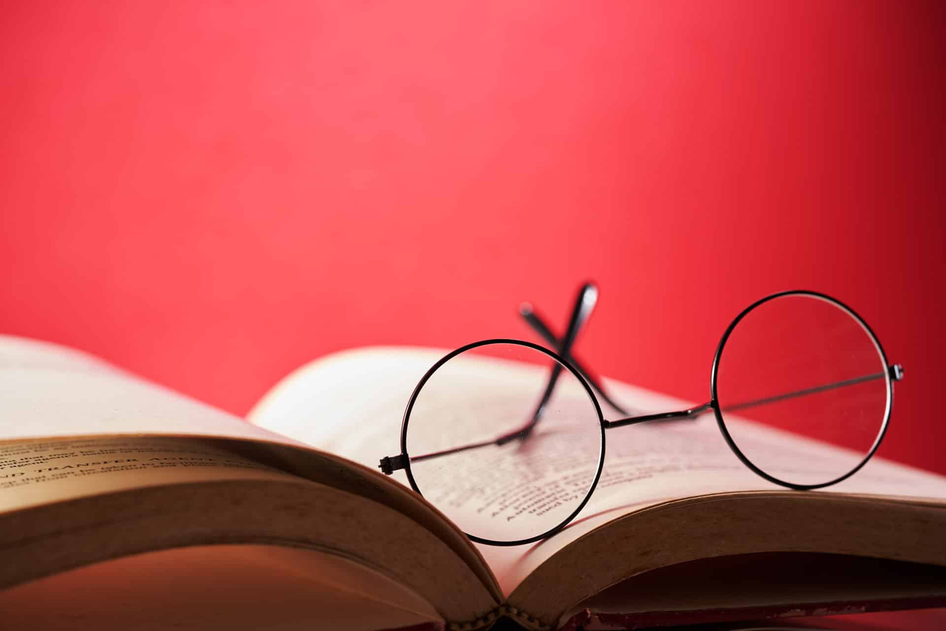 An open dictionary with reading glasses resting on it